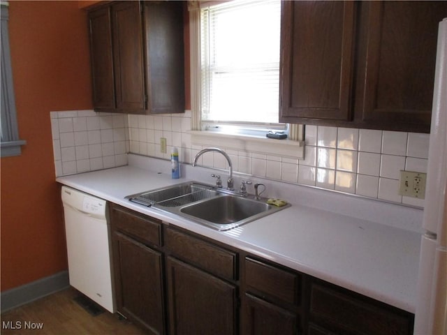 kitchen featuring white appliances, dark wood-style floors, a sink, light countertops, and backsplash