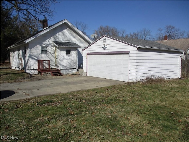 exterior space with a chimney, a front lawn, concrete driveway, an outdoor structure, and a garage