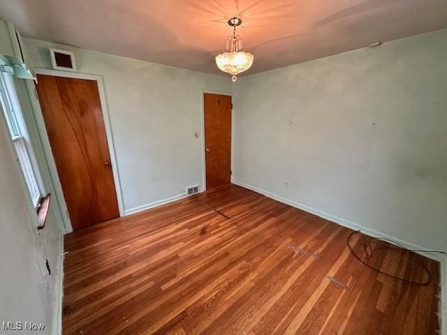 unfurnished room with visible vents, baseboards, and wood finished floors