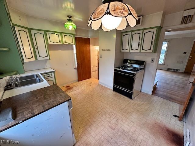 kitchen with visible vents, gas range, green cabinets, and a sink