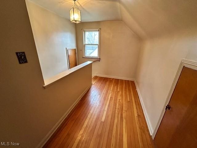 bonus room with baseboards, wood-type flooring, and vaulted ceiling