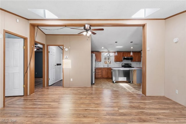 kitchen featuring light wood-type flooring, stainless steel appliances, brown cabinets, and a skylight