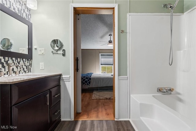 full bath featuring a ceiling fan, a textured ceiling, wood finished floors, shower / bath combination, and vanity