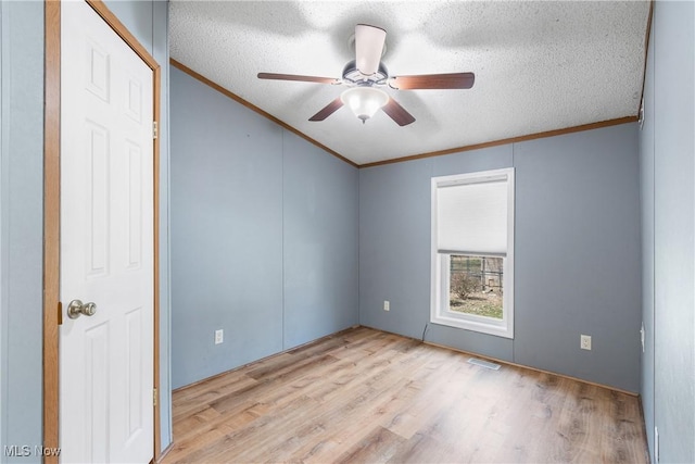 empty room featuring crown molding, wood finished floors, visible vents, and a textured ceiling