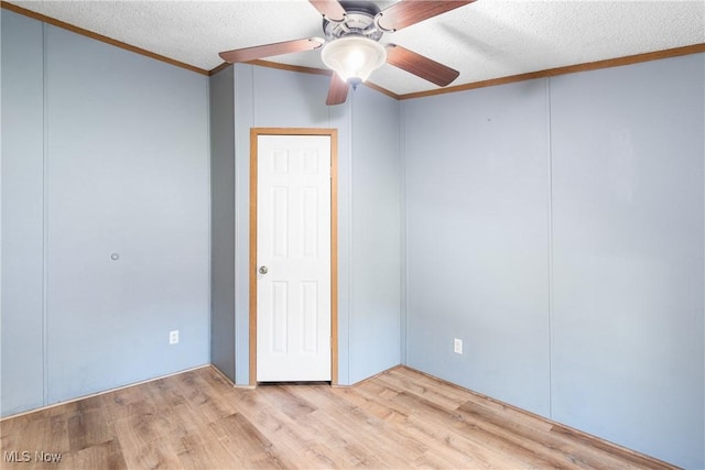 spare room featuring a textured ceiling, crown molding, ceiling fan, and wood finished floors