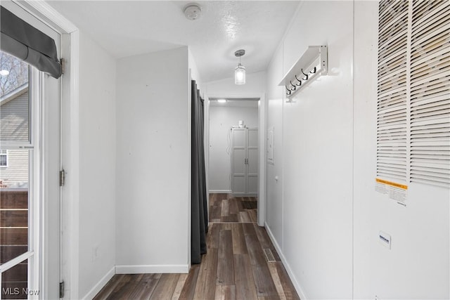 corridor featuring baseboards and dark wood-style flooring