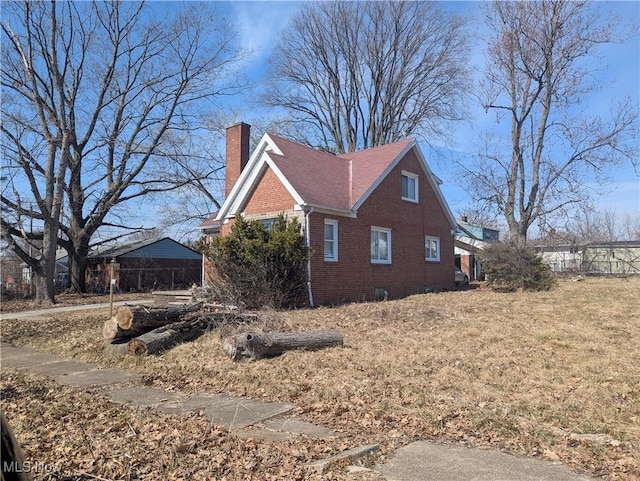 view of property exterior featuring brick siding, a chimney, and a lawn