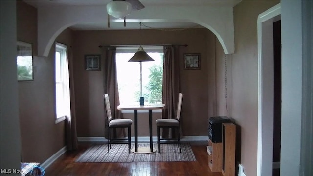 interior space with arched walkways, baseboards, and wood finished floors