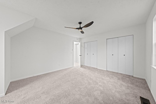 unfurnished bedroom with visible vents, two closets, carpet flooring, baseboards, and ceiling fan