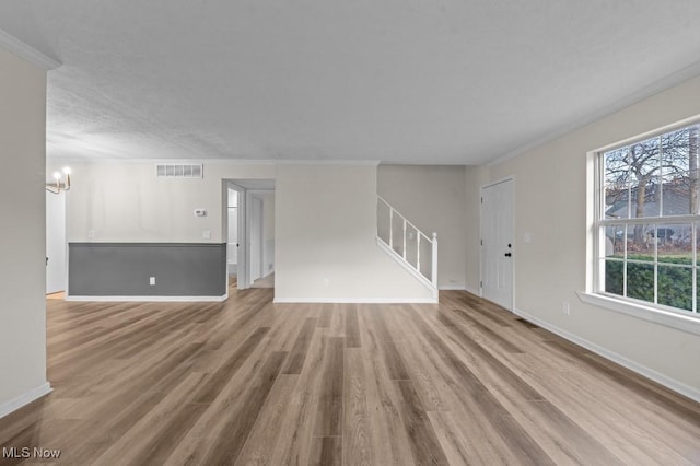 unfurnished living room featuring visible vents, wood finished floors, stairs, and ornamental molding