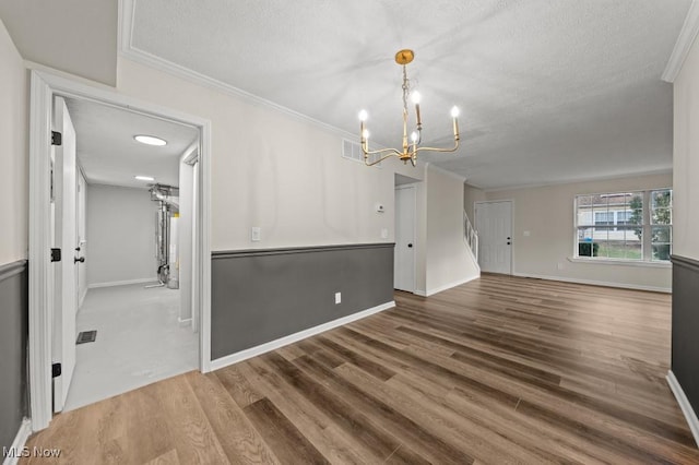 spare room featuring a notable chandelier, a textured ceiling, crown molding, and wood finished floors