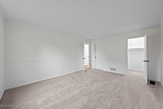 carpeted spare room with baseboards, visible vents, and ornamental molding