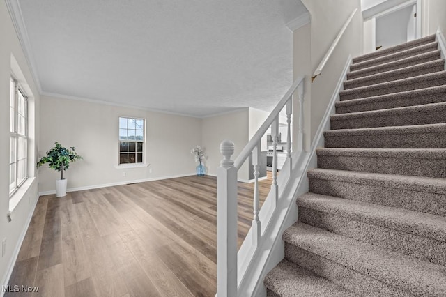 stairway with ornamental molding, baseboards, and wood finished floors