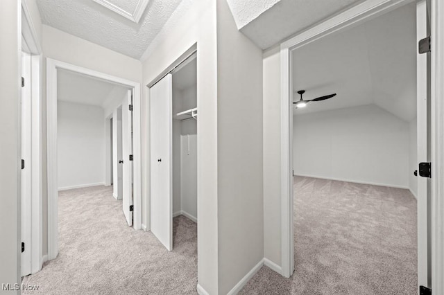 corridor featuring vaulted ceiling, a textured ceiling, and carpet floors