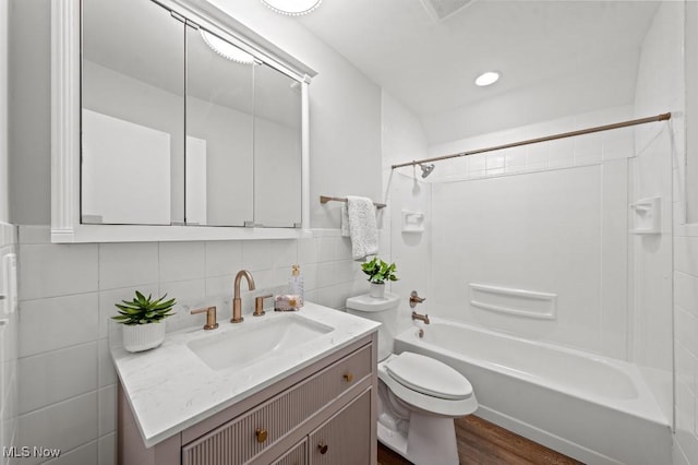 full bath featuring visible vents, toilet, tile walls, shower / bath combination, and vanity