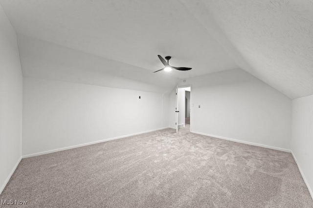 bonus room featuring carpet, a ceiling fan, baseboards, vaulted ceiling, and a textured ceiling