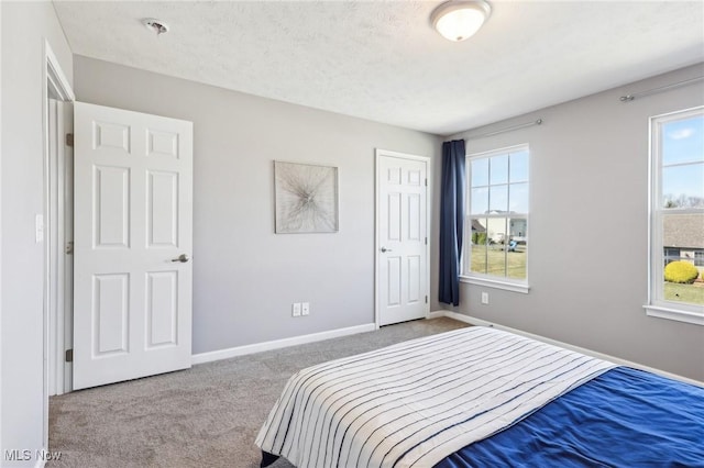 carpeted bedroom with a closet, baseboards, and a textured ceiling