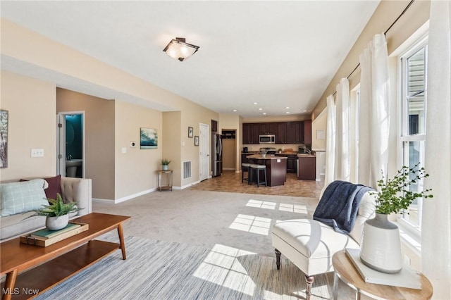 living room with visible vents, baseboards, and light colored carpet