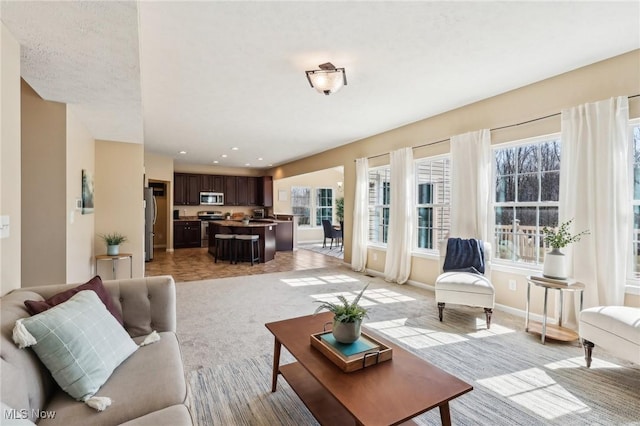 living room with recessed lighting, baseboards, and light colored carpet