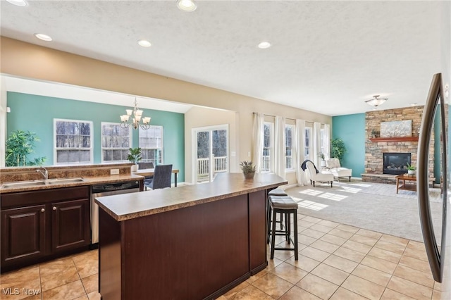 kitchen featuring light tile patterned floors, a fireplace, a sink, light carpet, and stainless steel dishwasher