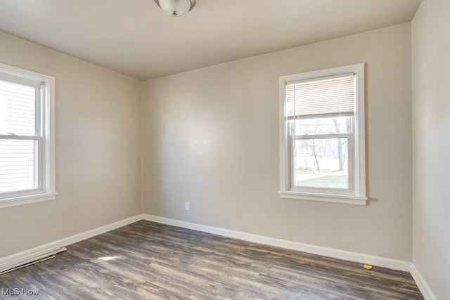 unfurnished room featuring baseboards, a healthy amount of sunlight, and dark wood-style floors