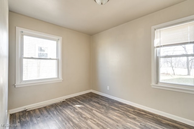 unfurnished room with a wealth of natural light, dark wood-type flooring, and baseboards