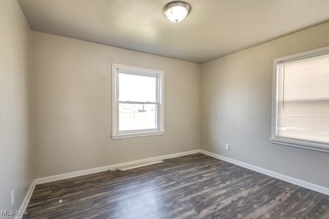 empty room featuring dark wood finished floors and baseboards