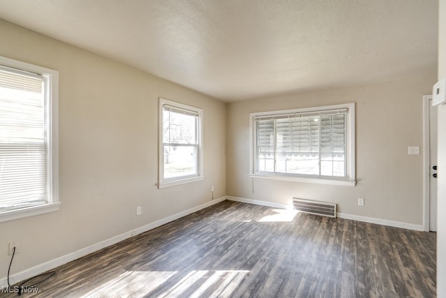 empty room with visible vents, baseboards, a textured ceiling, and wood finished floors