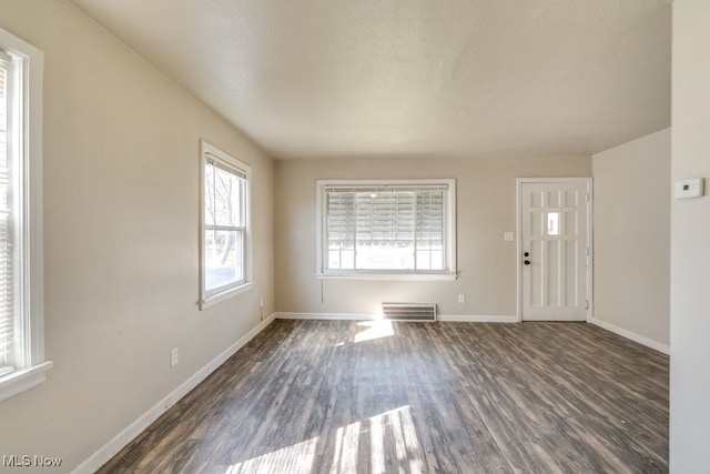 foyer featuring visible vents, baseboards, and dark wood-style flooring