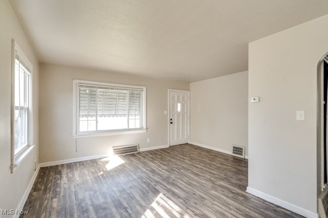 entryway featuring arched walkways, wood finished floors, visible vents, and baseboards