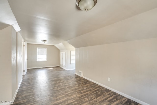 bonus room featuring visible vents, lofted ceiling, dark wood-type flooring, and baseboards