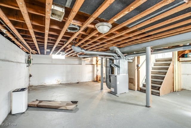 unfinished basement featuring heating unit and stairway