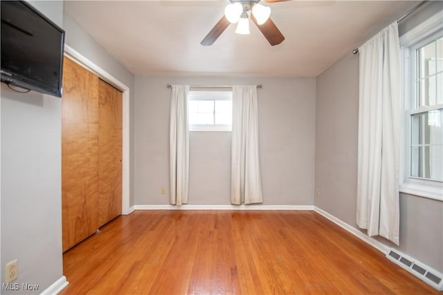 unfurnished bedroom with visible vents, a ceiling fan, wood finished floors, a closet, and baseboards