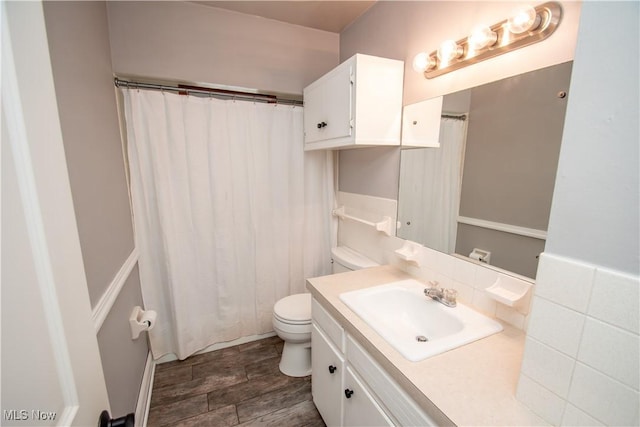 bathroom with toilet, vanity, and wood finished floors