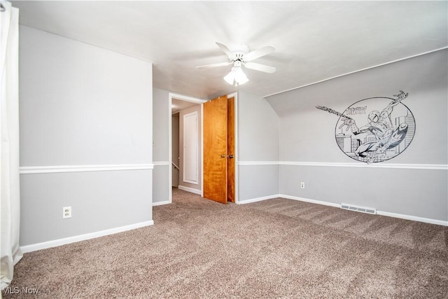 carpeted spare room with visible vents, baseboards, lofted ceiling, and a ceiling fan