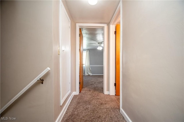 hallway with an upstairs landing, carpet, and baseboards