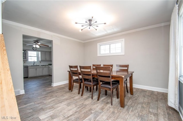 dining space with a chandelier, baseboards, ornamental molding, and light wood finished floors