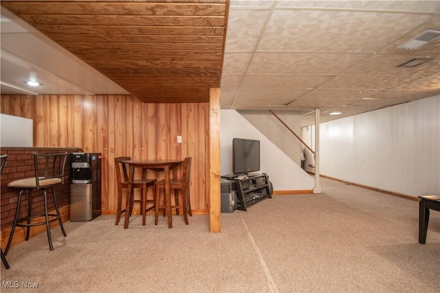 interior space featuring wooden walls, visible vents, stairway, a dry bar, and carpet floors