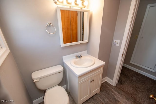 bathroom with toilet, vanity, baseboards, and wood finished floors