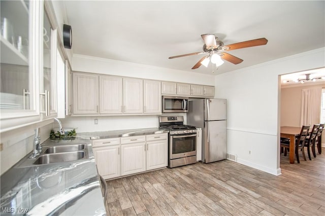 kitchen featuring light wood finished floors, ornamental molding, stainless steel appliances, and a sink