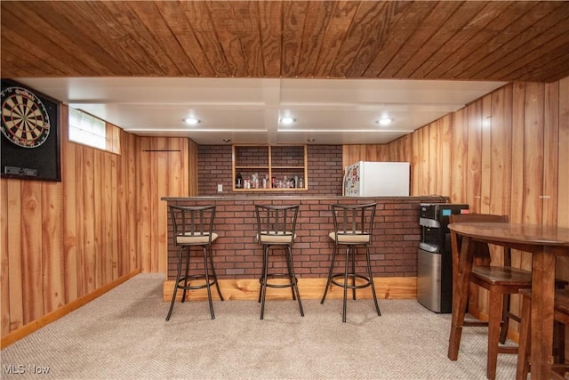 bar with a dry bar, wooden walls, and refrigerator