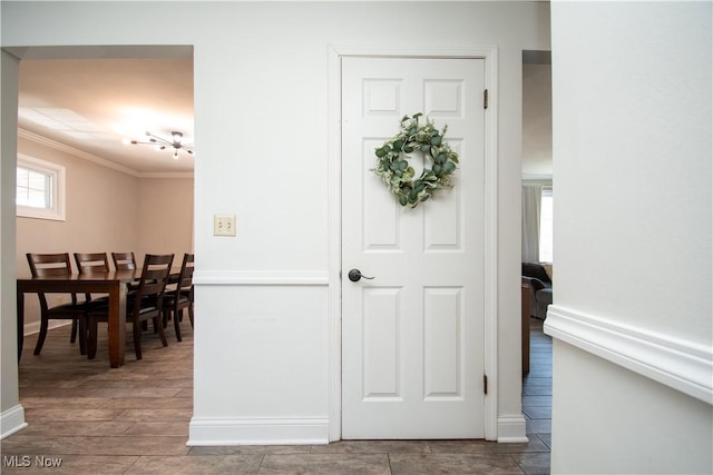 foyer entrance with wood tiled floor, baseboards, and ornamental molding