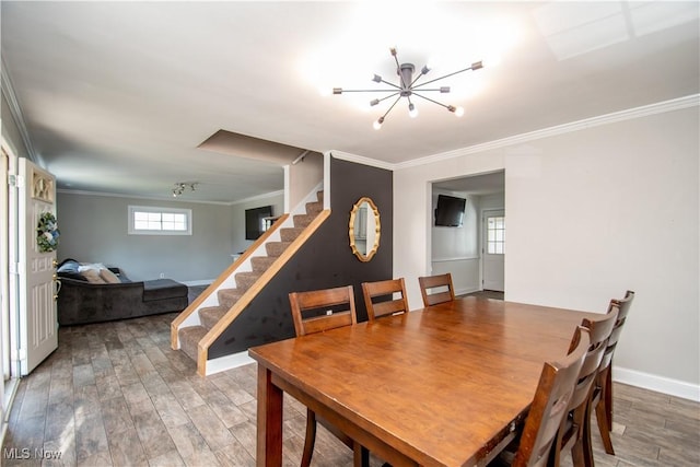 dining space featuring crown molding, baseboards, a chandelier, light wood-type flooring, and stairs