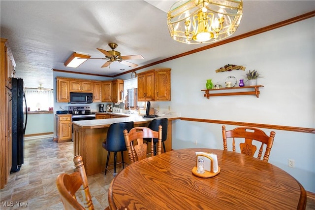 kitchen with black appliances, ornamental molding, a sink, a peninsula, and brown cabinetry