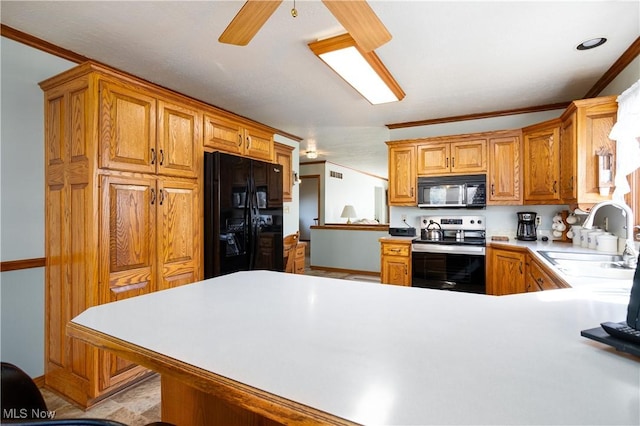 kitchen featuring crown molding, light countertops, a peninsula, black appliances, and a sink