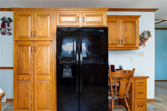 kitchen featuring brown cabinetry, black fridge with ice dispenser, and baseboards