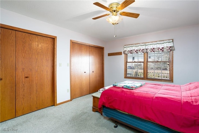 carpeted bedroom featuring baseboards, two closets, and a ceiling fan