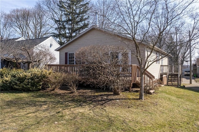 view of side of property featuring a yard, a wooden deck, and stairway