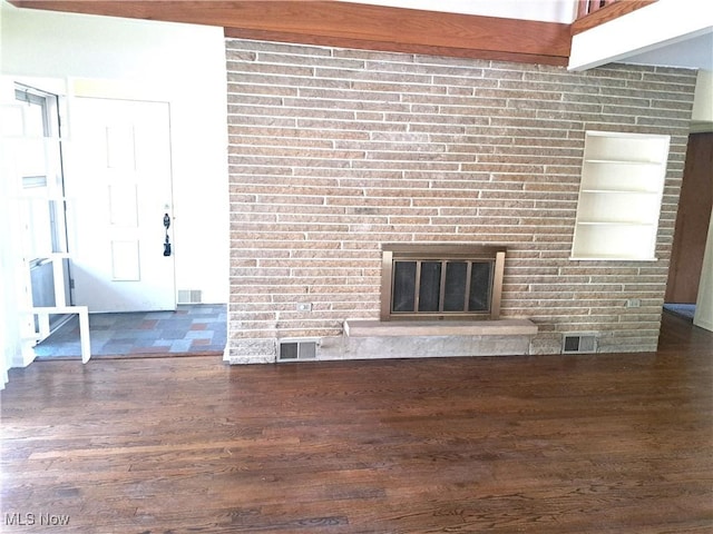 unfurnished living room featuring visible vents, beam ceiling, wood finished floors, and a fireplace