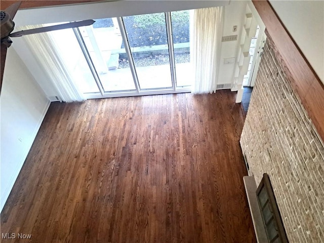 unfurnished living room featuring dark wood finished floors, stairs, and baseboards